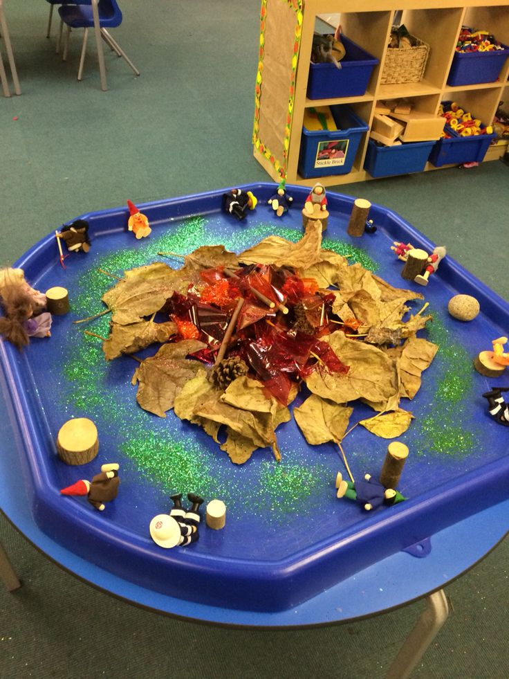 a child's play table with leaves and toys on it in a classroom setting