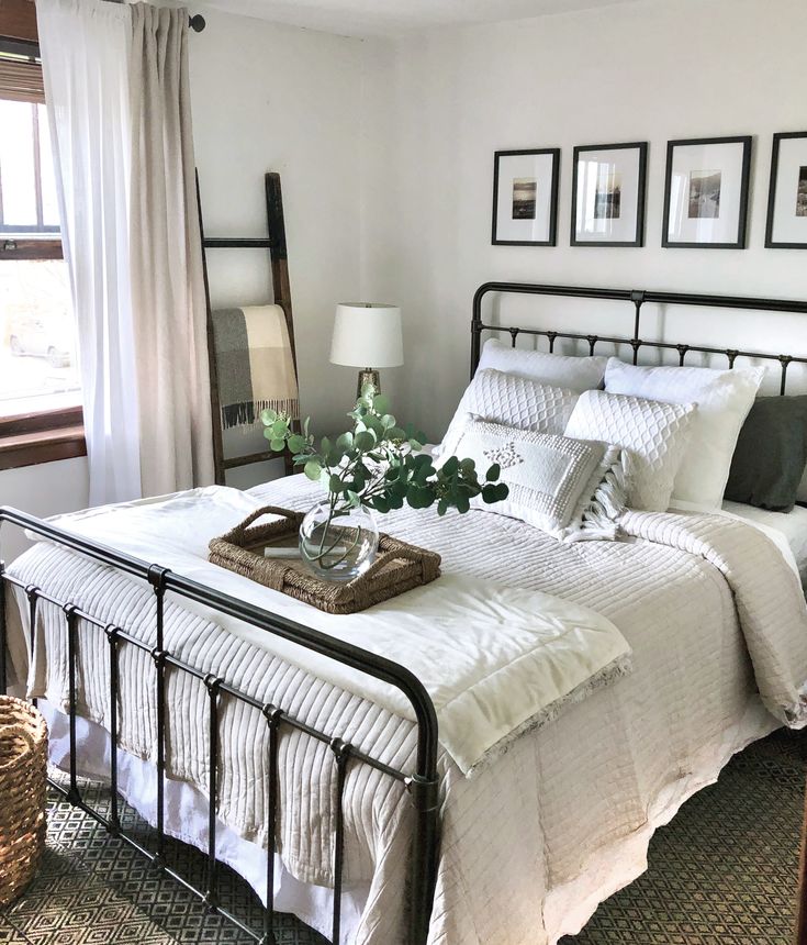 a bed with white sheets and pillows in a bedroom next to a basket filled with flowers