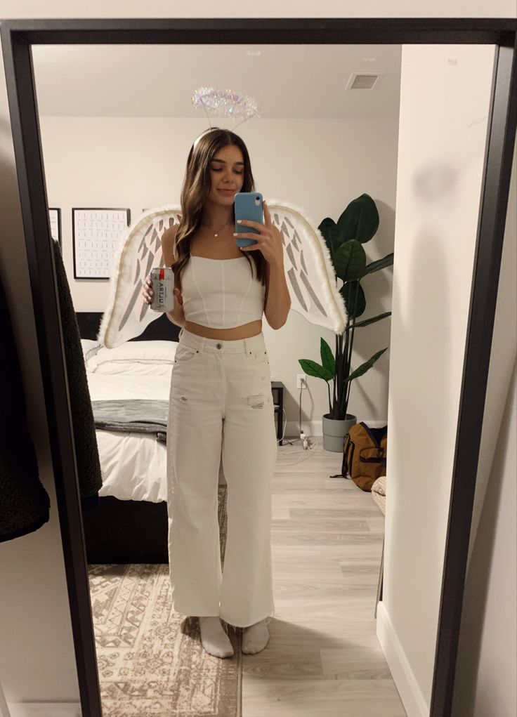 a woman taking a selfie in the mirror with an angel wings above her head