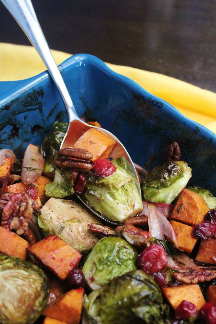 brussels sprouts, brussel sprouts and cranberries in a blue bowl with a spoon