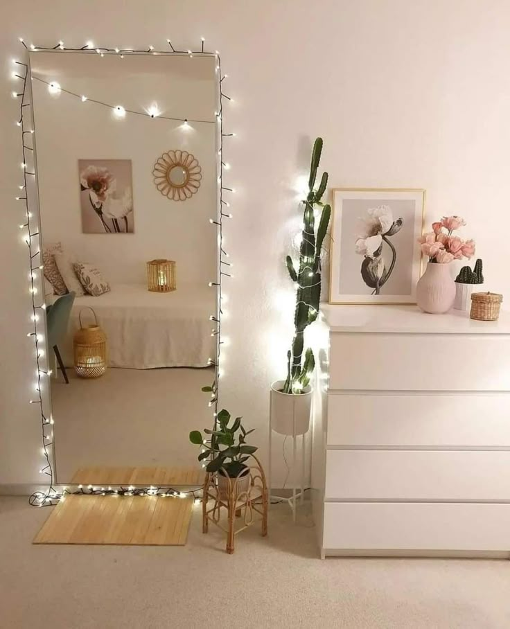 a bedroom with white furniture and string lights on the wall, along with a large mirror