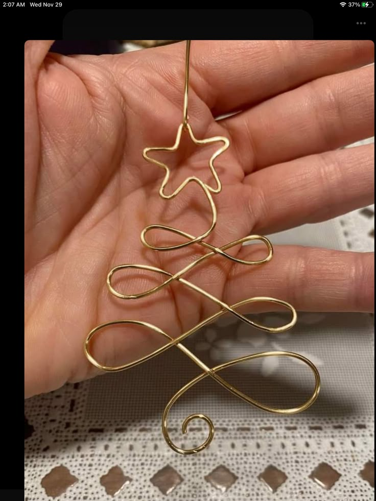 a hand holding a gold wire christmas tree ornament