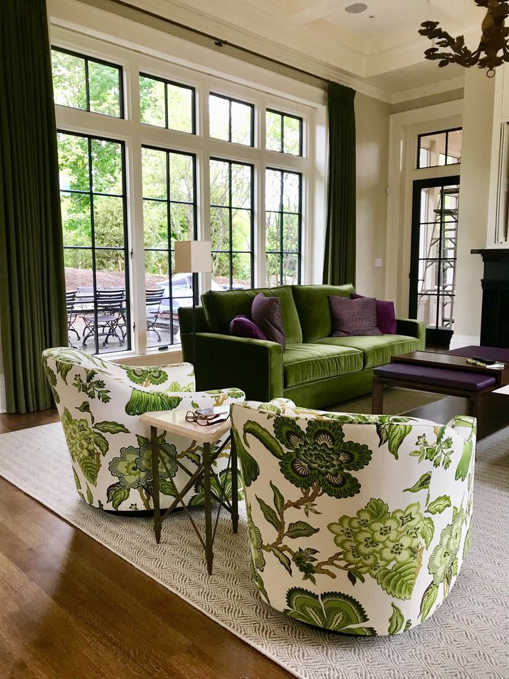 a living room filled with lots of furniture and large window covered in green drapes