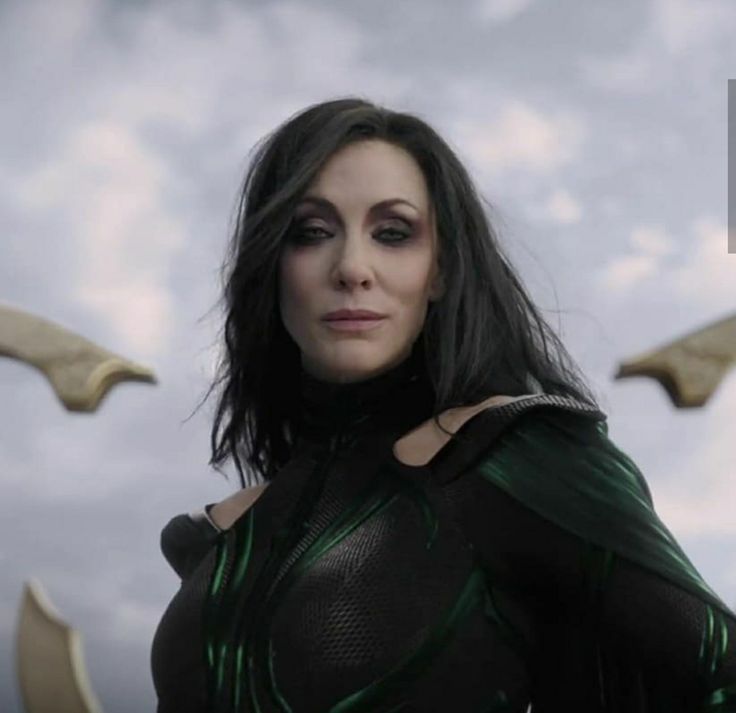 a woman in a green and black costume standing next to two birds flying above her