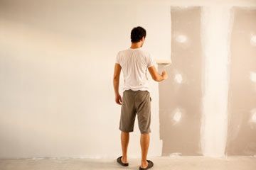 a man standing in front of a white wall with lights on it and his back to the camera