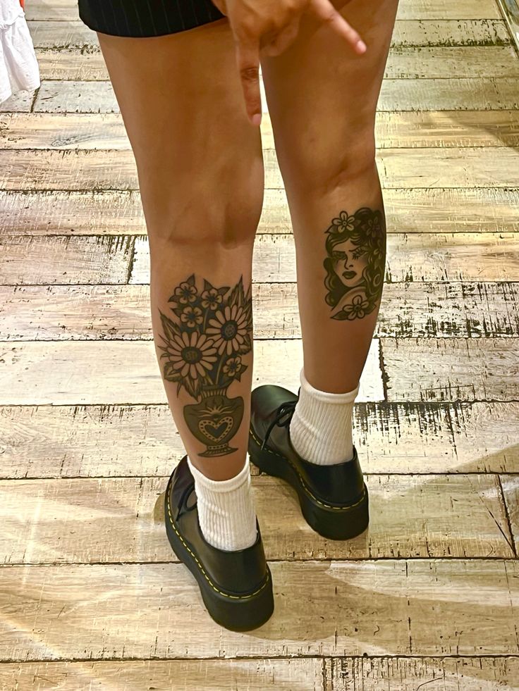 a person with tattoos on their legs and feet pointing to something in the distance while standing on a wooden floor