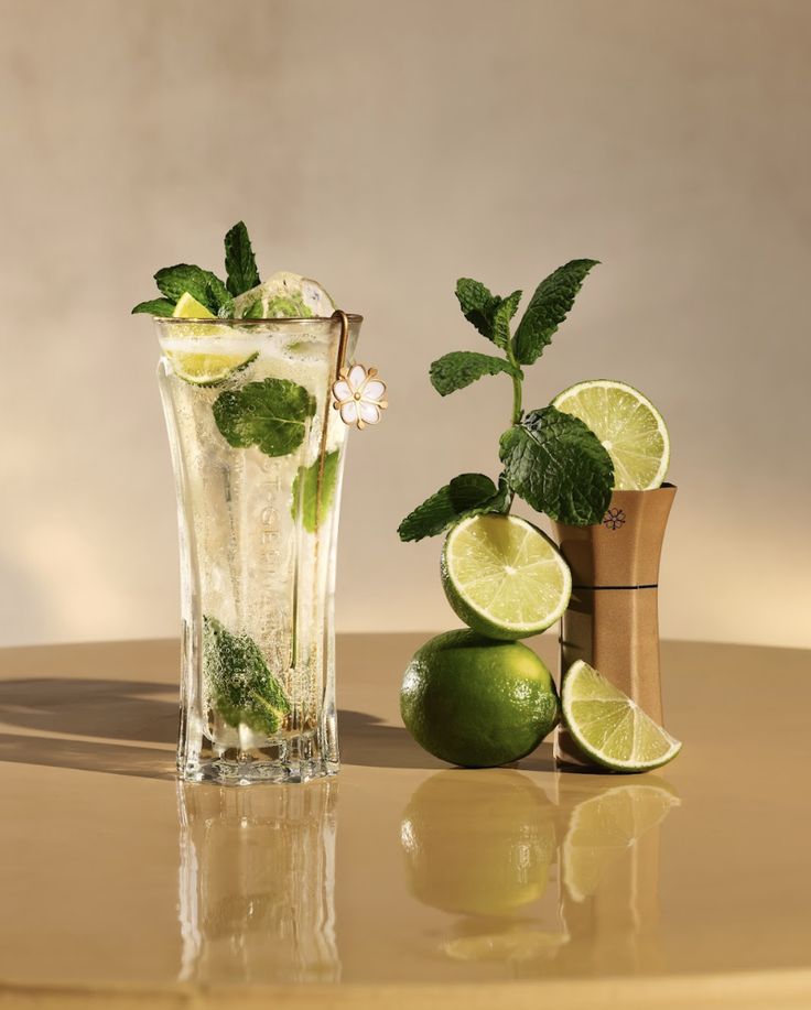 two glasses filled with ice and limes on a table