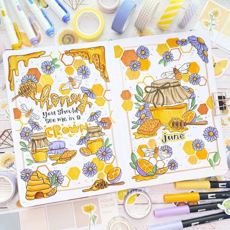 an open notebook with bees and honey on it, surrounded by other items such as markers