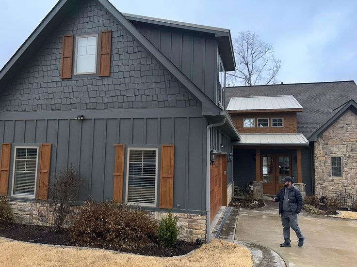 a man standing in front of a gray house