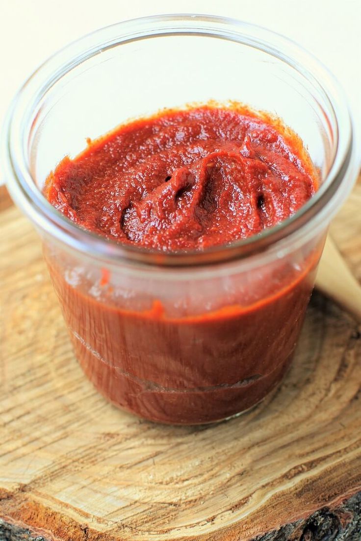 a jar of sauce sitting on top of a wooden cutting board