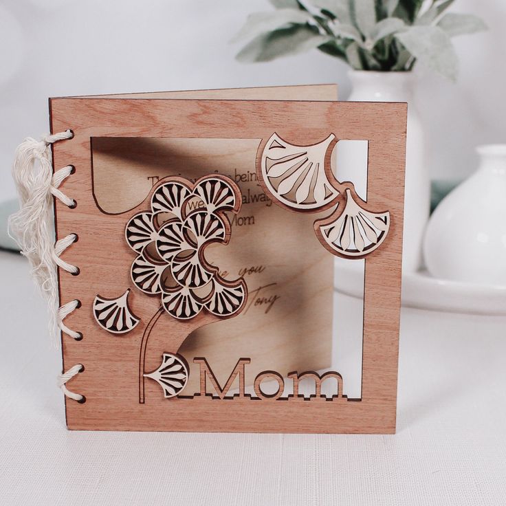 a mother's day card with flowers and leaves on the front in a wooden frame