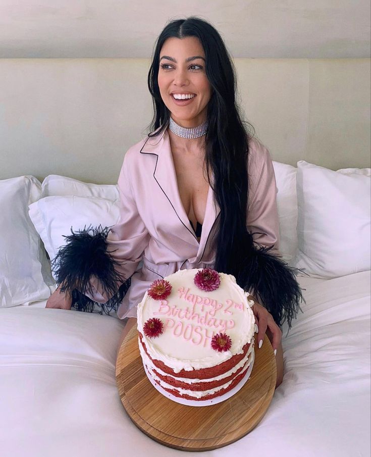 a woman sitting on top of a bed holding a cake