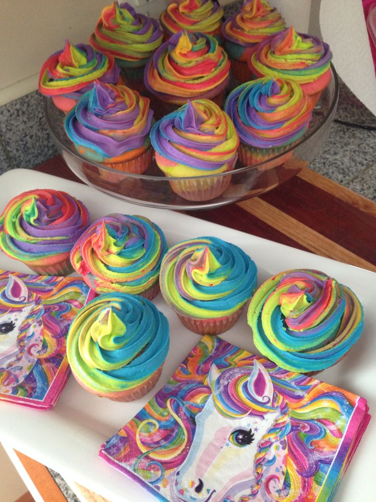 cupcakes with rainbow frosting are on a table