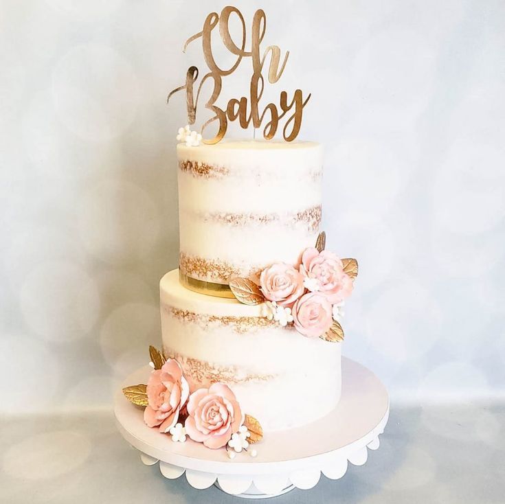 a three tiered cake with pink flowers and gold lettering that says baby on top