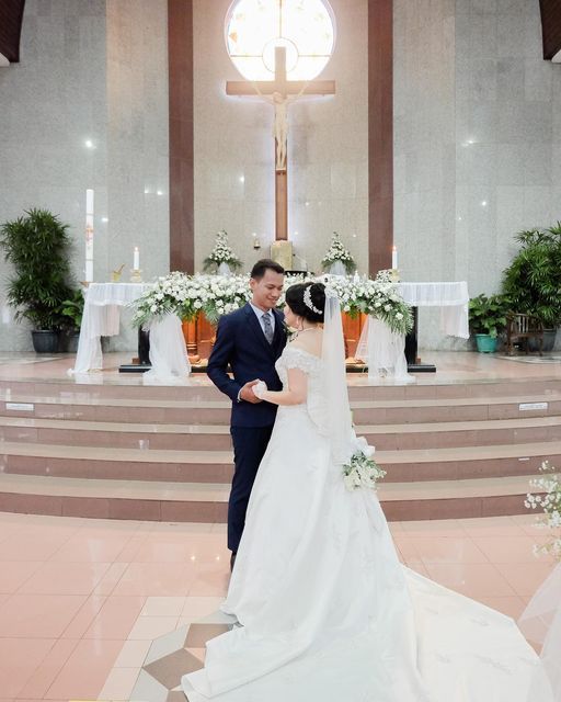 a bride and groom standing in front of the alter