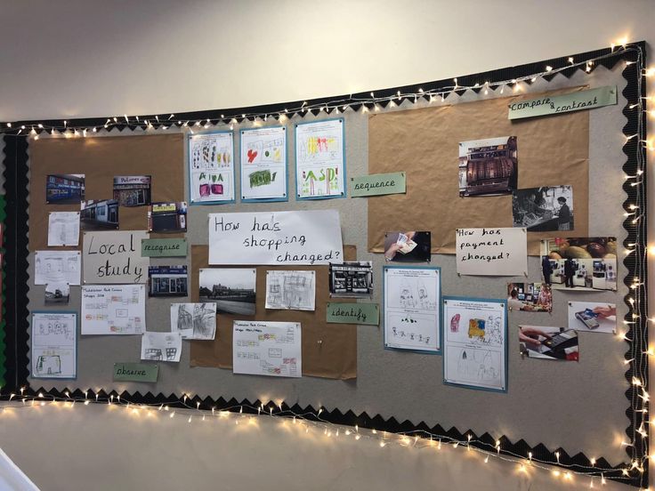 a bulletin board is covered with papers and lights on the wall in an office building