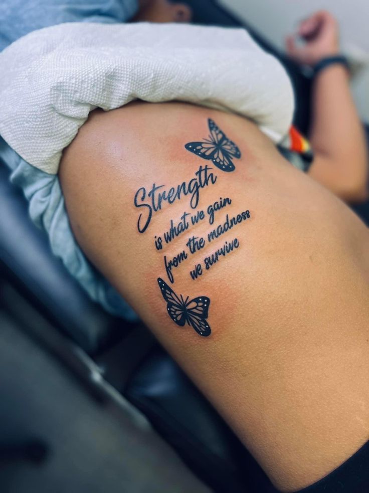 the back of a woman's thigh with butterflies on it, saying strength is what we