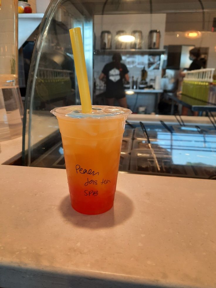 a plastic cup with a straw in it sitting on a counter