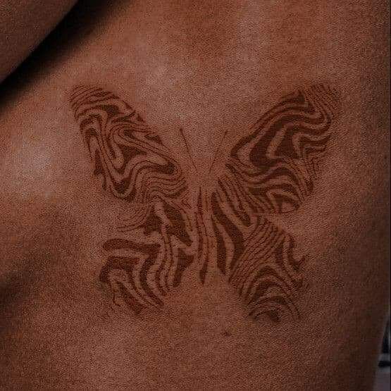 a close up of a person's back with a butterfly tattoo on his chest