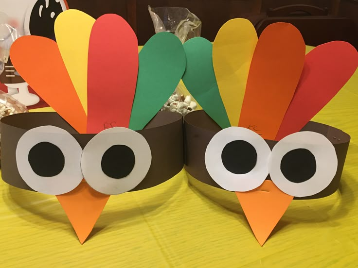 two paper turkeys sitting on top of a table