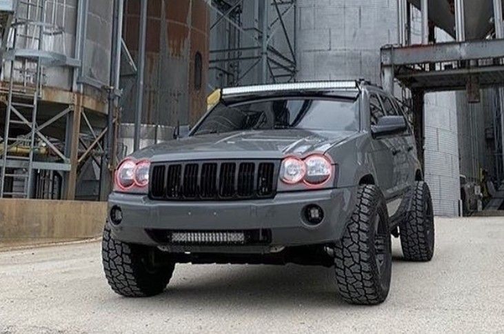 a gray jeep parked in front of a large industrial building with scaffolding on the side