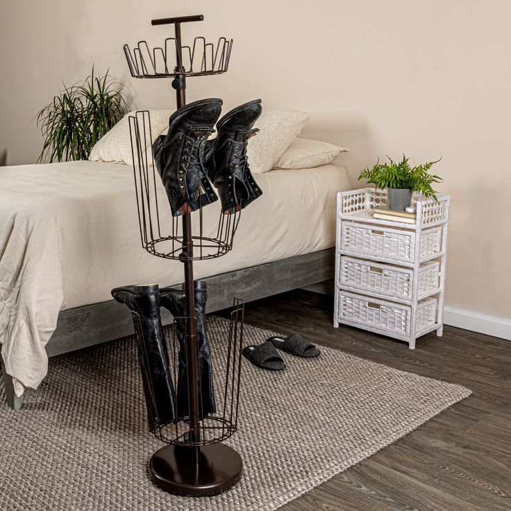 a pair of black boots are sitting on a rack in front of a white bed