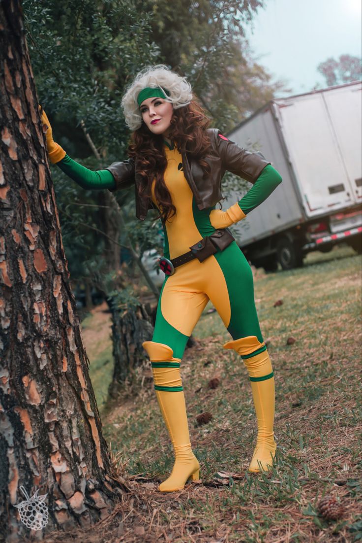 a woman in a costume standing next to a tree with her hands on her hips