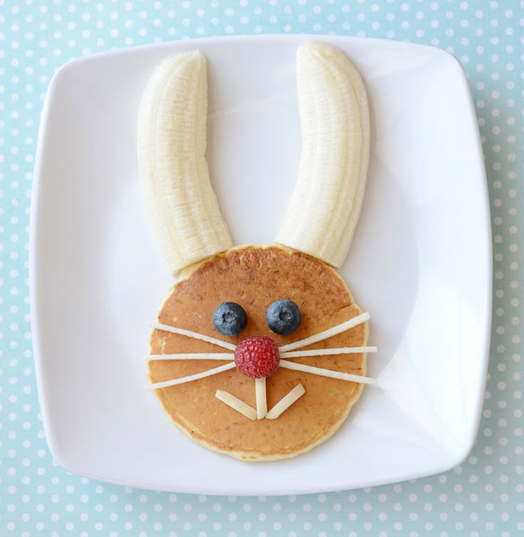 a white plate topped with pancakes covered in banana's and blueberries as a bunny face