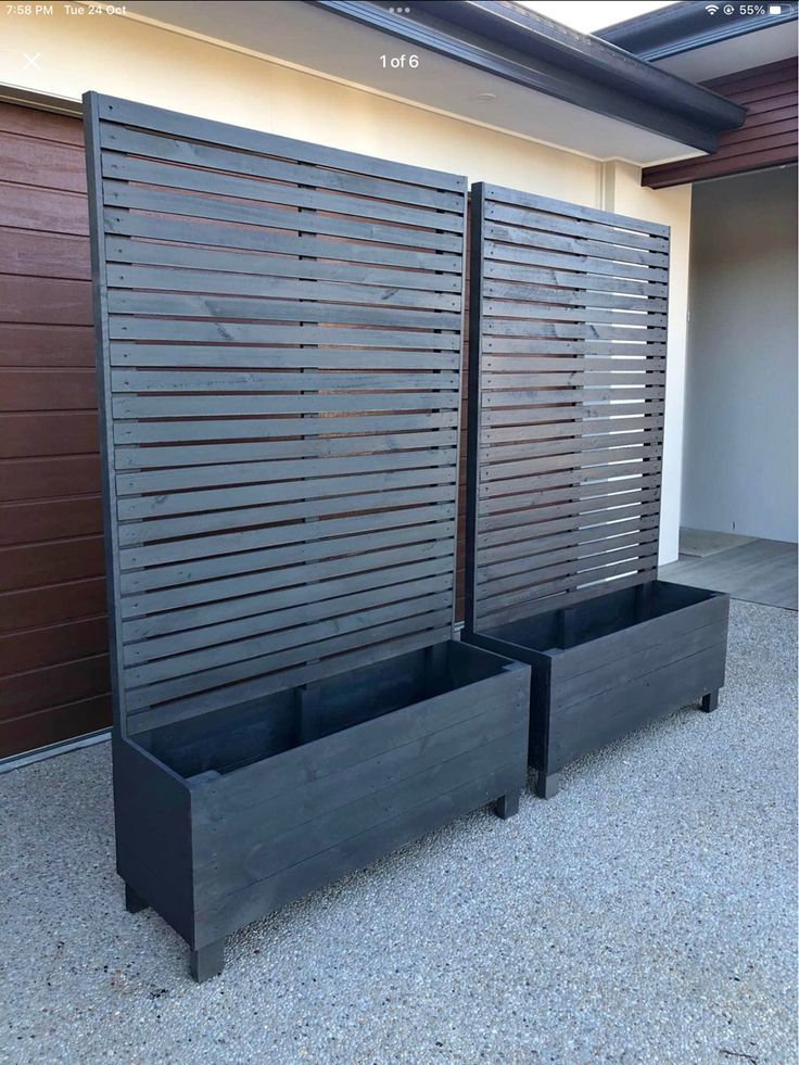 two black planters sitting next to each other in front of a garage door with shutters