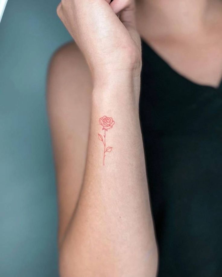 a woman's arm with a small rose tattoo on the left side of her wrist