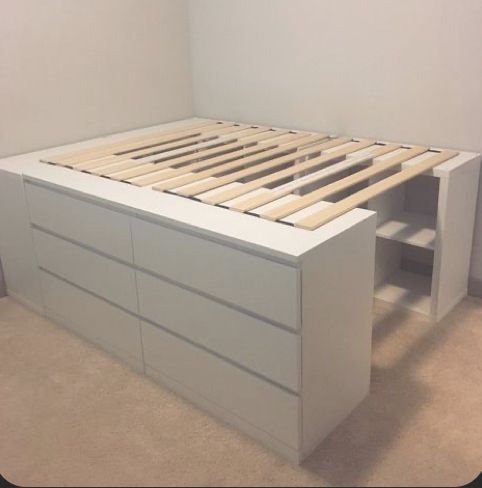 a white bed frame with drawers underneath it