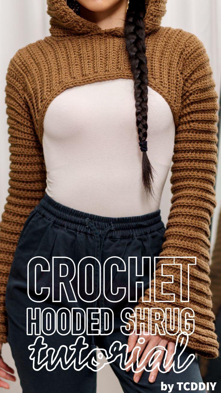 a woman with braids wearing a brown sweater and black pants, standing in front of a