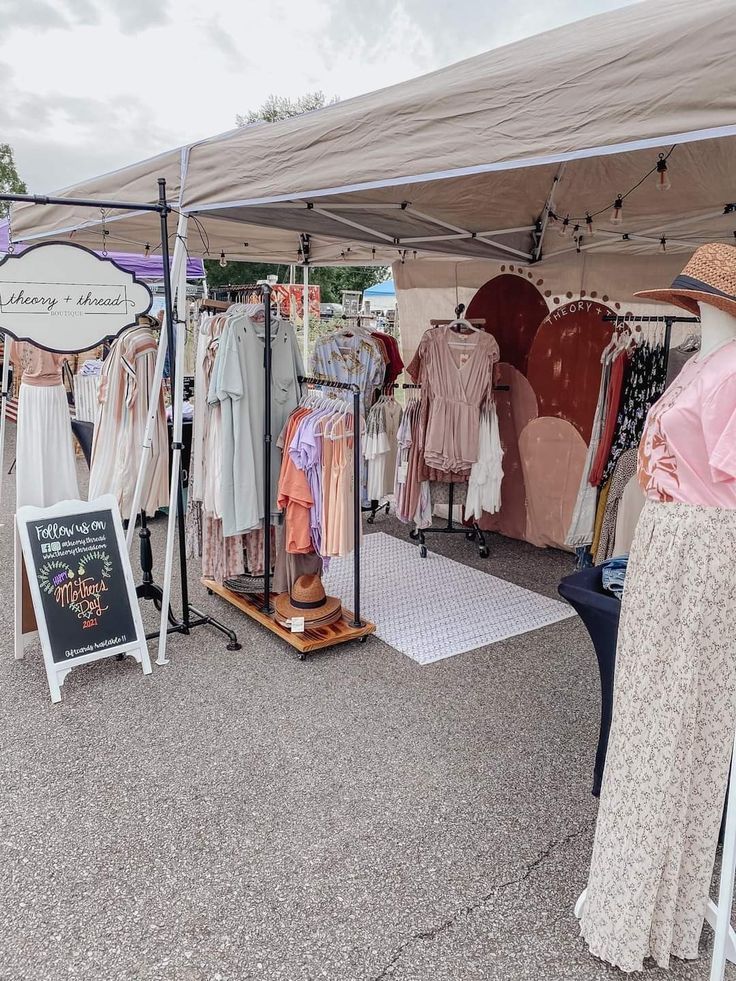 a woman looking at clothing on display under a tent