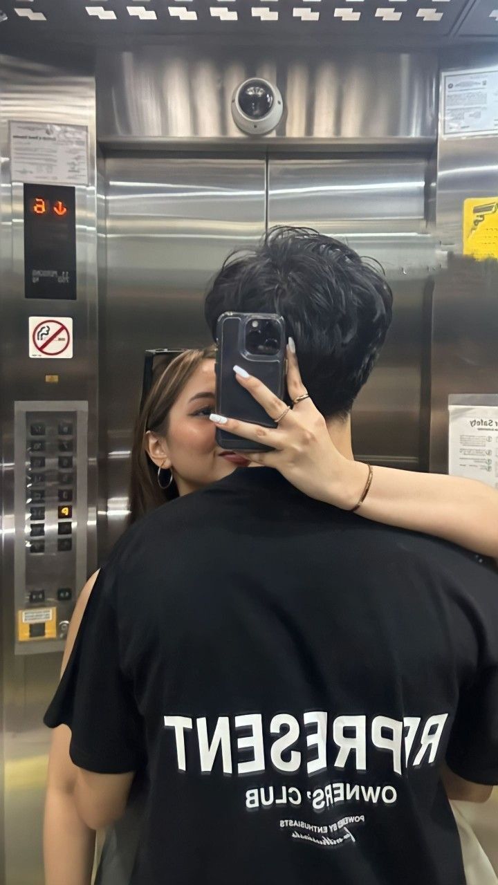 a man and woman taking a selfie in front of an elevator