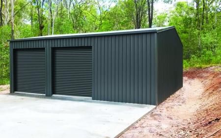 two garages in the middle of a dirt area with trees and bushes behind them