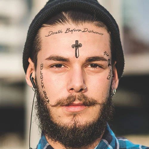 a man with tattoos on his face and cross drawn on the forehead is looking at the camera