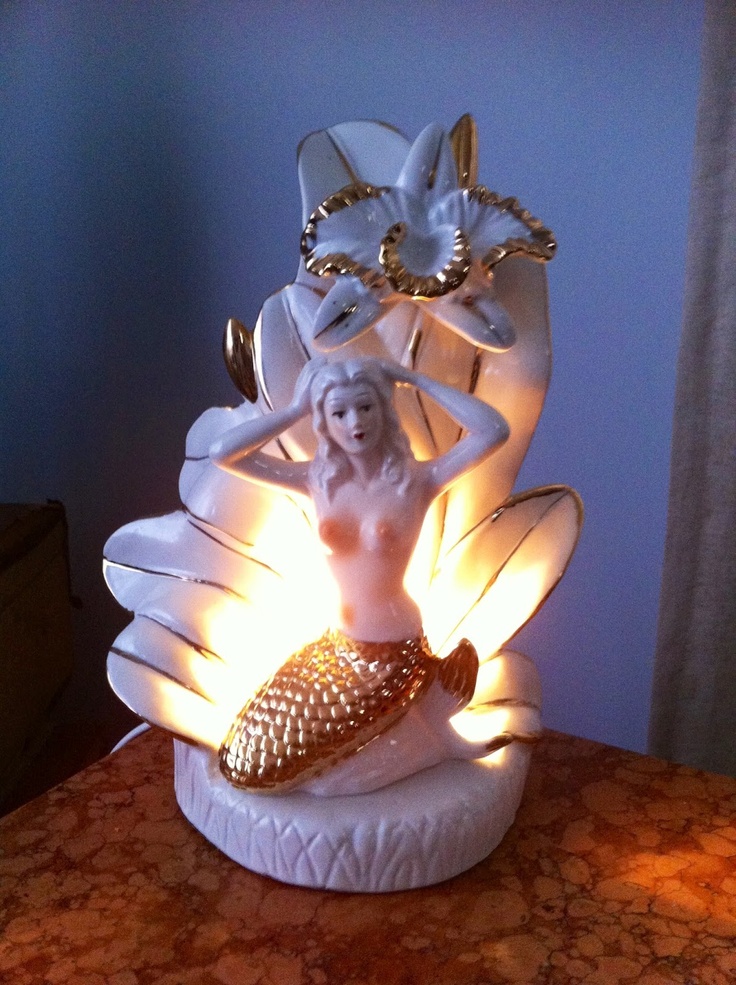 a white figurine sitting on top of a table next to a light bulb