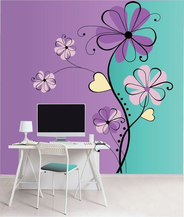 a desk with a computer on top of it in front of a purple wall mural