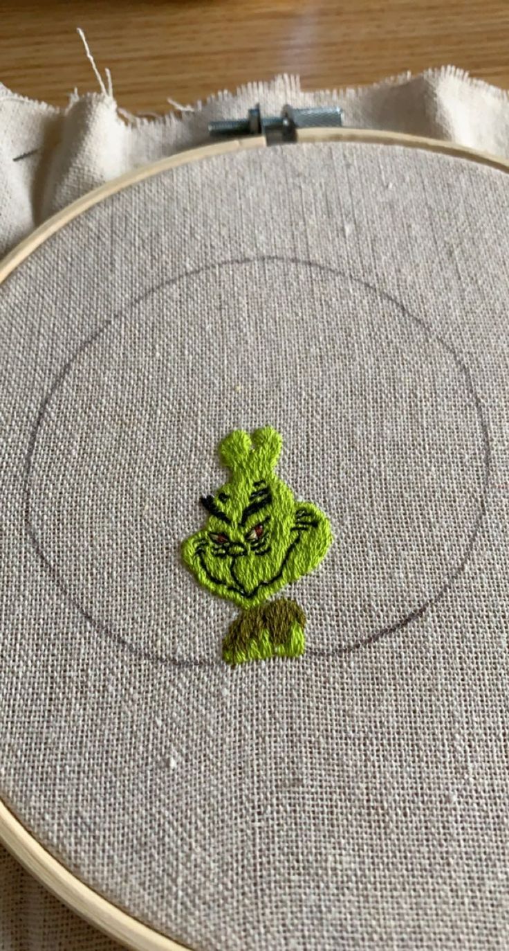 a close up of a embroidery on a piece of cloth with a small green leaf