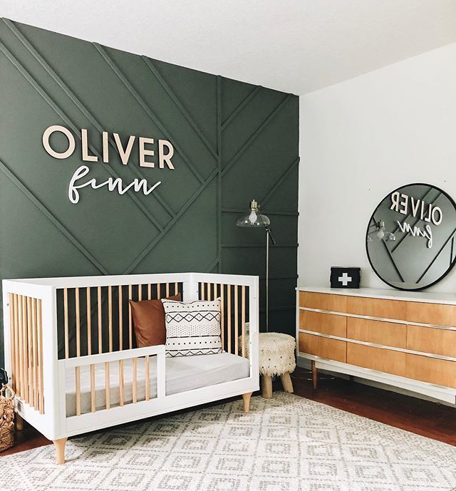 a baby's room decorated in green and white with a wooden dresser next to it