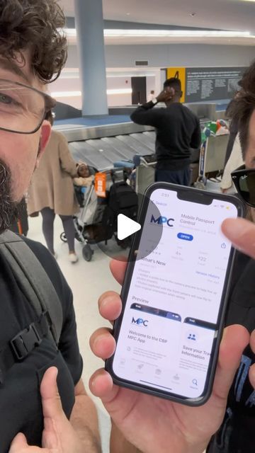 two men holding up their cell phones in an airport