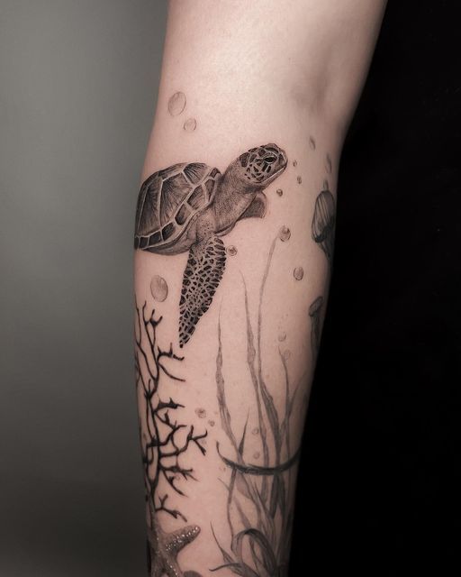 a woman's arm with a turtle and seaweed tattoo on the left forearm