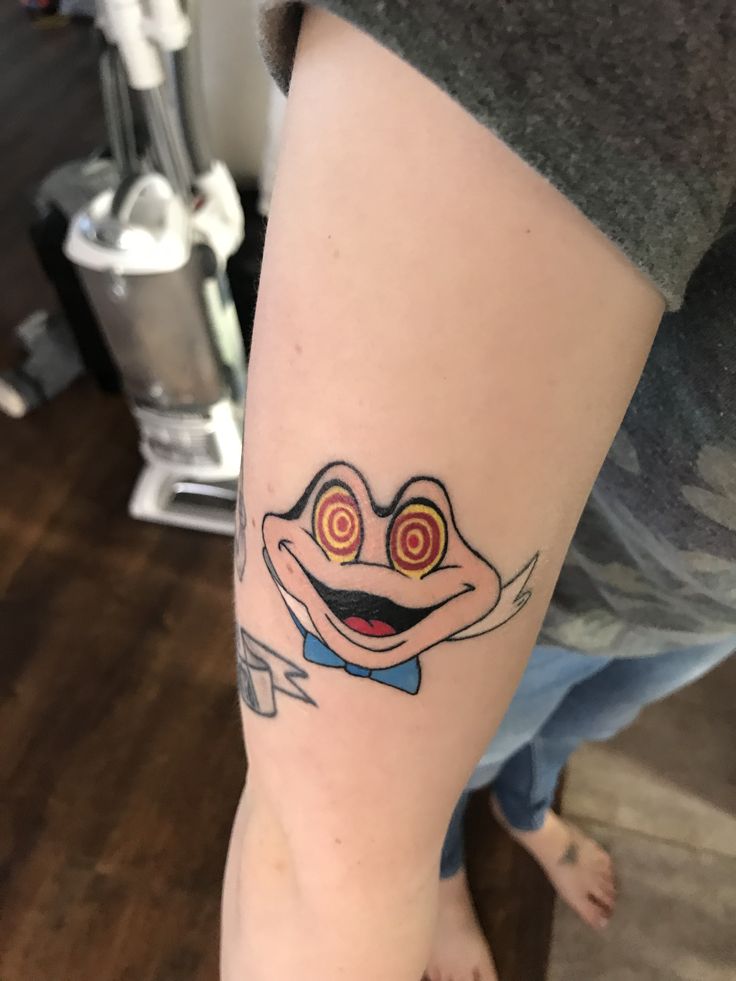 a person with a tattoo on their arm that has an image of a smiling frog