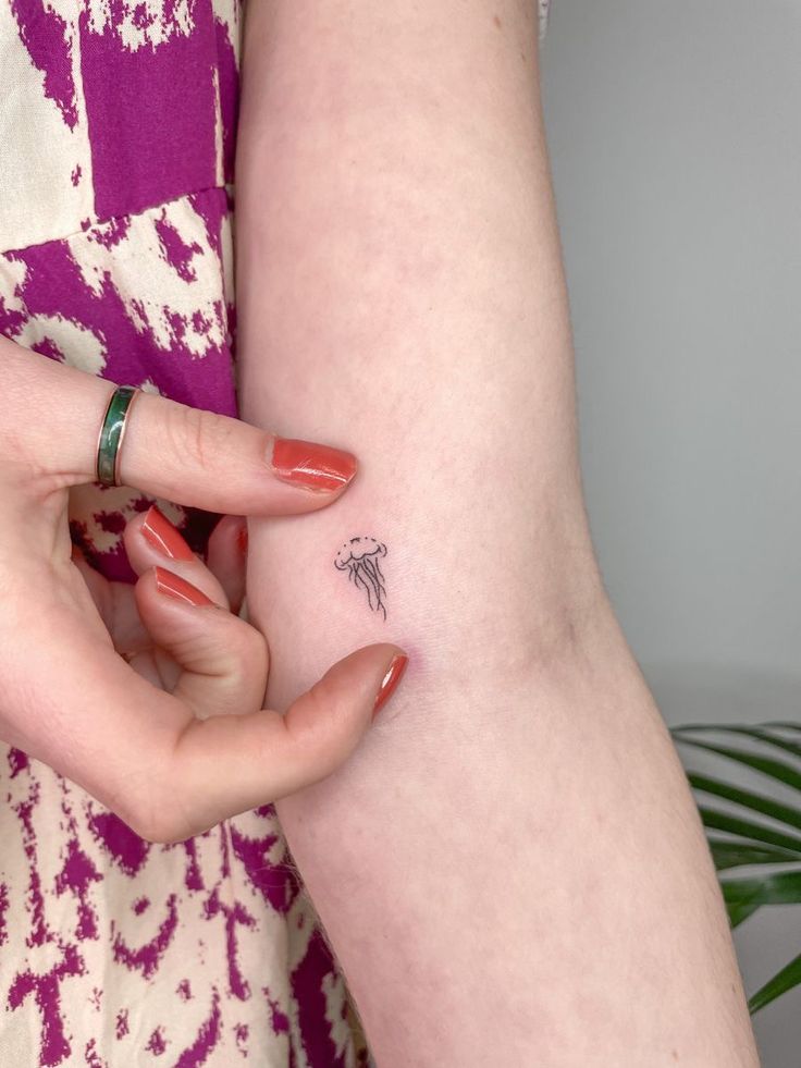 a woman holding onto her arm with a small tattoo on it's left side