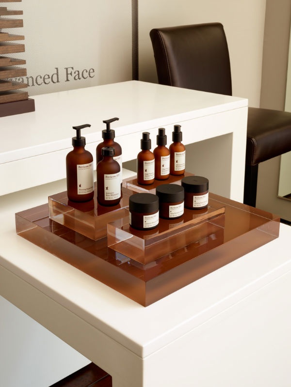 several bottles of hand lotion on a clear tray sitting on top of a white table