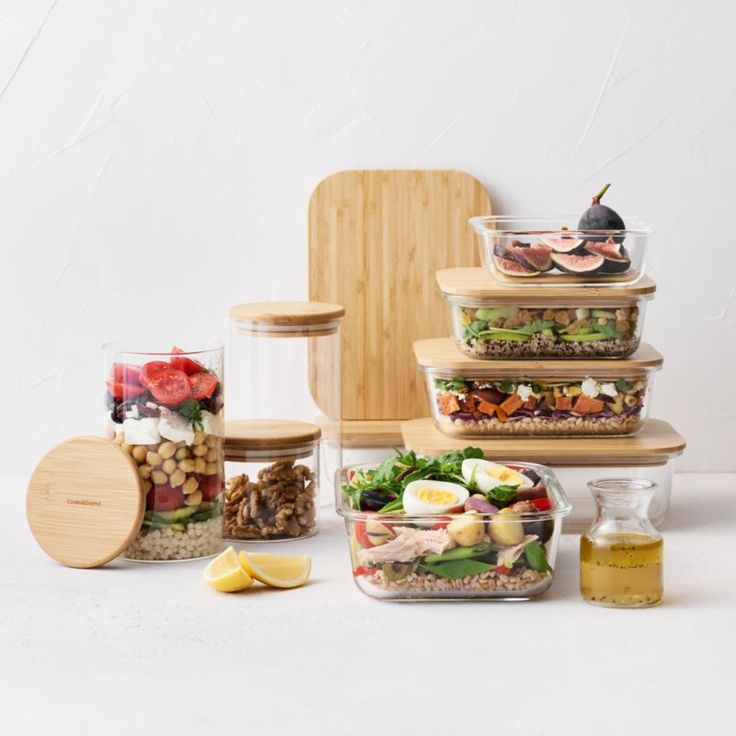 several glass containers filled with food sitting on top of a white table next to a cutting board