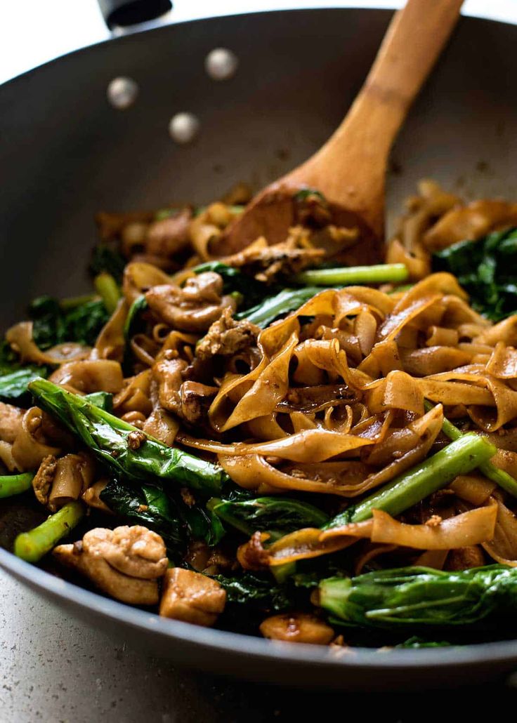 stir fried noodles with mushrooms and spinach in a pan