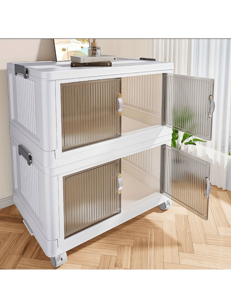 a white cabinet sitting on top of a hard wood floor next to a potted plant