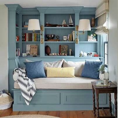 a room that has some blue bookshelves with pillows on it and a couch in the corner