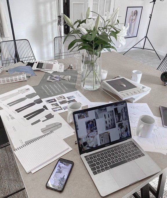 an open laptop computer sitting on top of a wooden table next to a vase filled with flowers